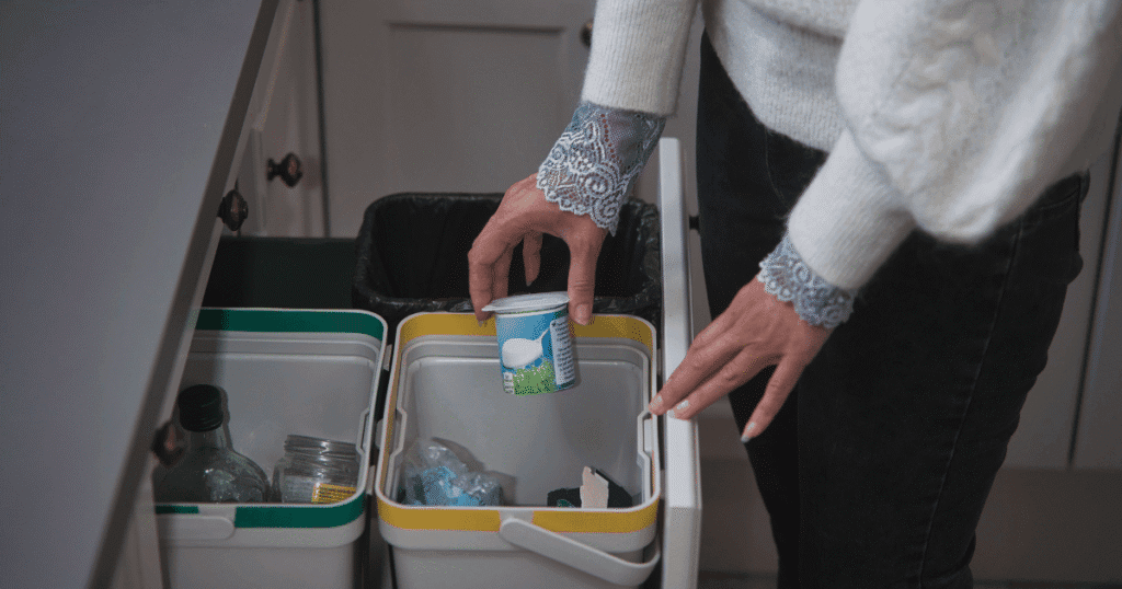 Comment éviter les 10 erreurs de tri les plus fréquentes ? 1 main de femme triant des déchets, verre, pot de yaourt